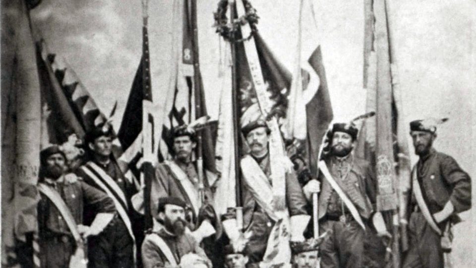 Skupina praporečníků se slavnostními prapory delegací spolků, které přijely do Plzně na oslavu svěcení prapora zdejšího Sokola v roce 1868