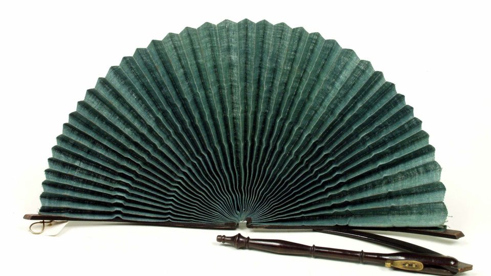 Vějíř kruhový (parasol, „plzeňské vadrle“). List ze zeleného impregnovaného plátna, jemně plisovaného. Konstrukce z černě barveného dřeva, soustružená skládací rukojeť kombinovaná kovovým otočným kloubem a očkem pro zajištění rozevřeného vějíře