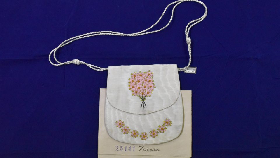 Dámská kabelka z bílého hedvábí s vyšívanými květy ze stužek. Kabelka pochází z rodiny purkmistra Petáka