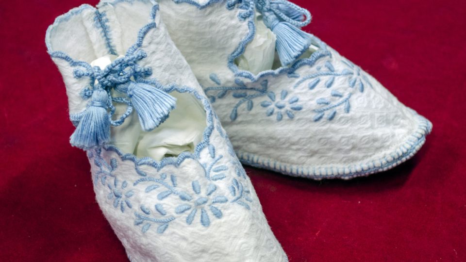 Bílé bavlněné kojenecké látkové botičky s modrou florální výšivkou. 20.–30. léta 20. století