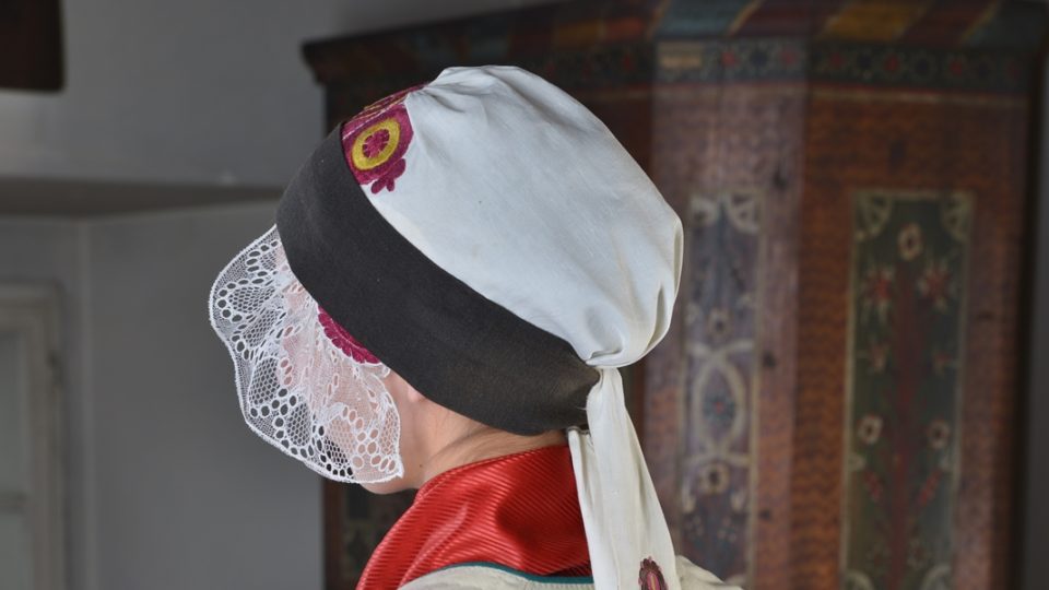 Vdaná žena z Chotěšovska s tzv. ženským vínkem vázaným přes čepec, vínek pestře vyšívaný zakončený paličkovanou krajkou
