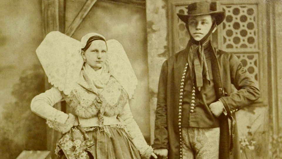Historická fotografie páru v plzeňském kroji – vdaná žena s manželem (holubice se „zalomenými“ křídly pro vdanou ženu)