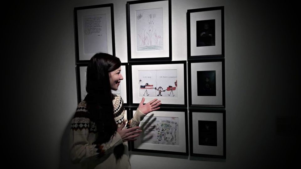 Asistentka kurátora Adéla Kristejnová ukazuje, která část expozice představuje fotografie dětí, obrázky a dopisy